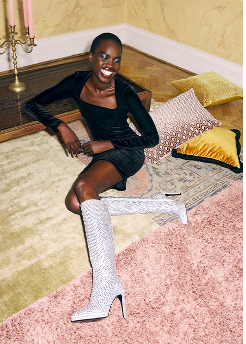 Female model sitting on the carpet wearing Russell and Bromley Spotlight crystal knee high boot